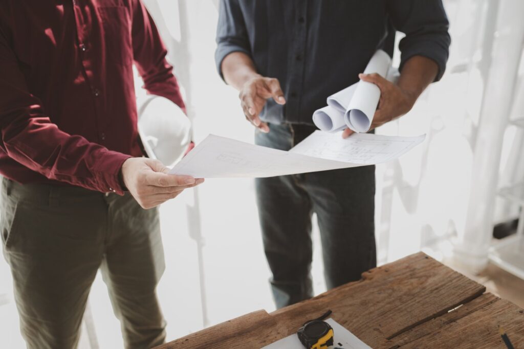 Commercial buildings are being evaluated by architects on what type of construction they need to be built, Engineers are designing a structure according to blueprints.